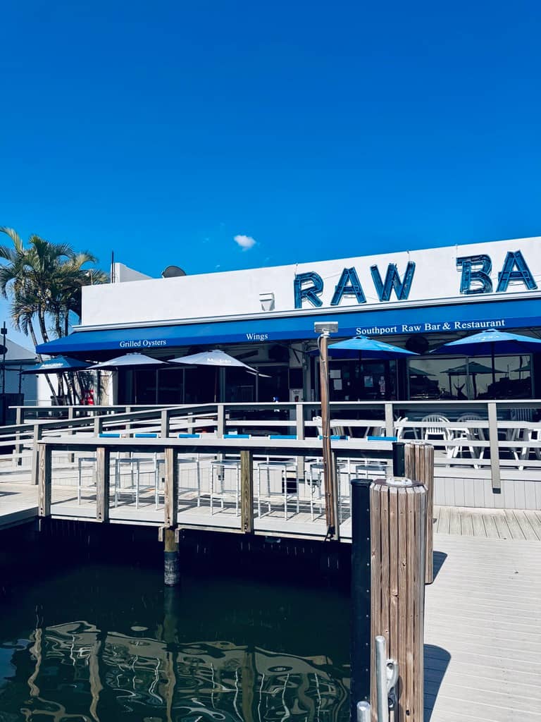 The Raw Bar building and its blue awning seen from the dock under a deep blue sky