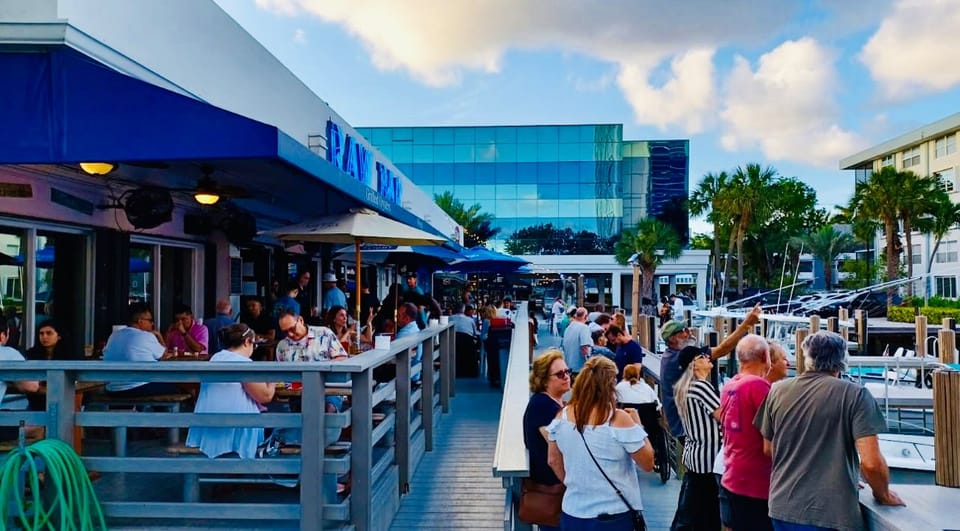 Guests on the waterfront deck in the early evening, boats docked alongside
