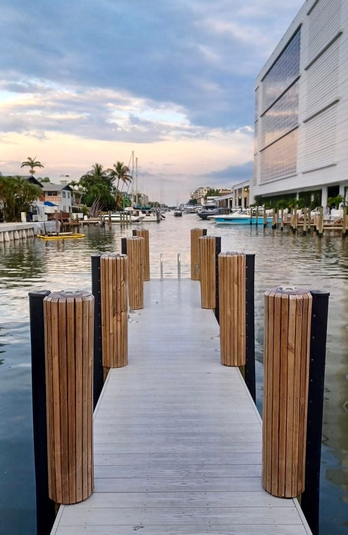 The dock between wooden pilings at dusk, the canal and its boats beyond