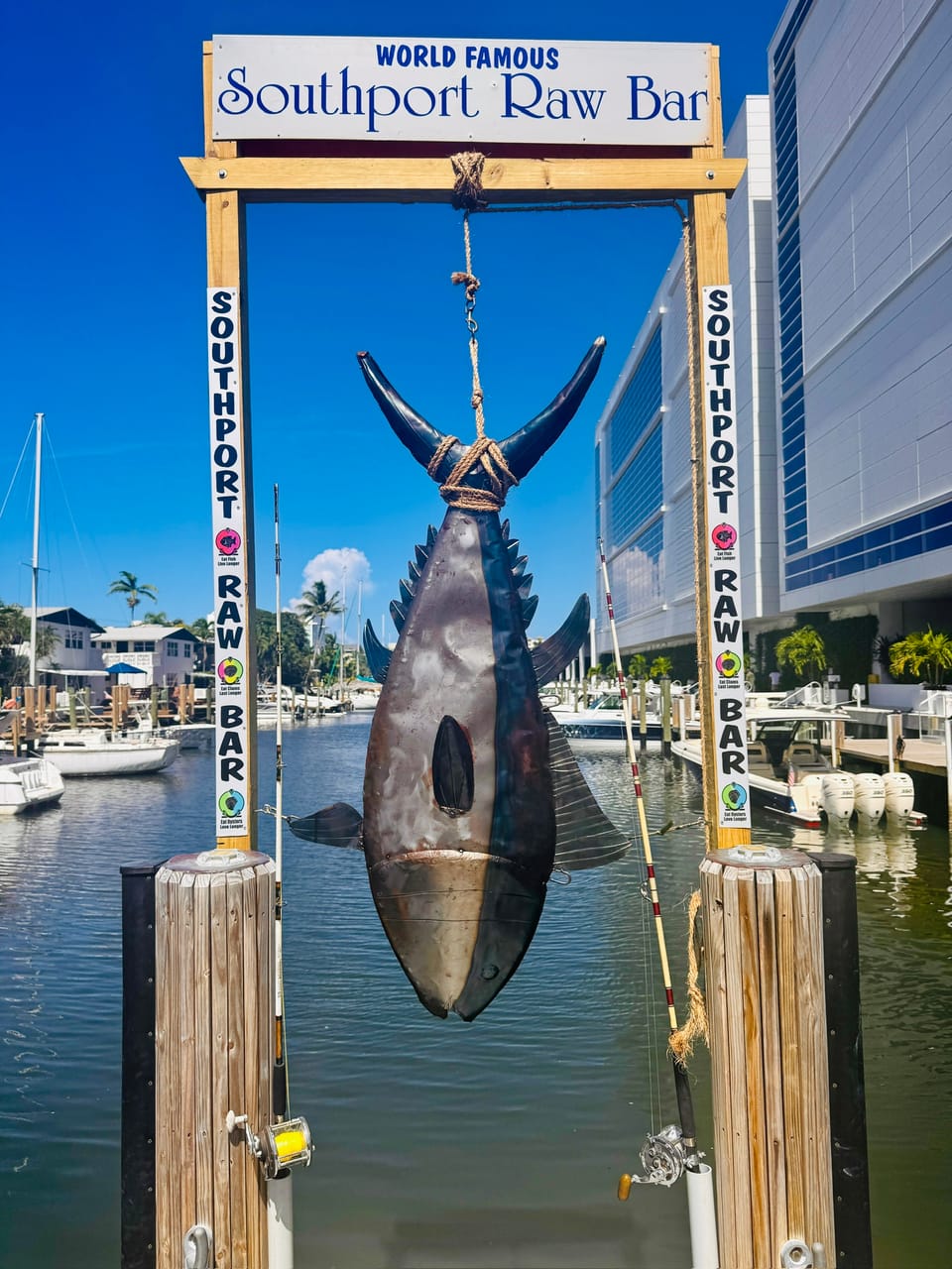 A big fish hanging under the World Famous Southport Raw Bar sign on the dock