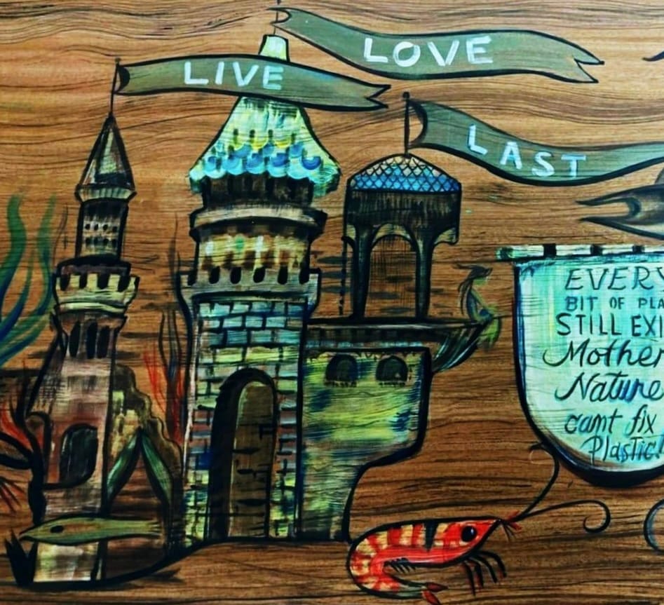 A painted mural of a castle under ribbons reading Live, Love, Last