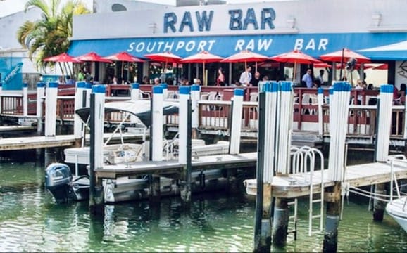 The Raw Bar and its red umbrellas seen from the water, boats at the dock