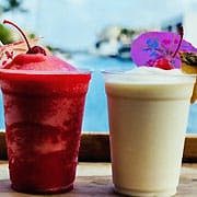 Two frozen drinks on a table by the water